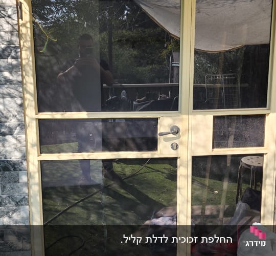 דלת זכוכית עם מסגרת מתכת, השתקפות אדם בזכוכית
